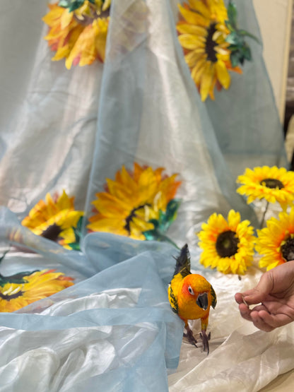 Mukhi sky blue hand painted organza dupatta with sunflower artwork styled in a soft floral setting